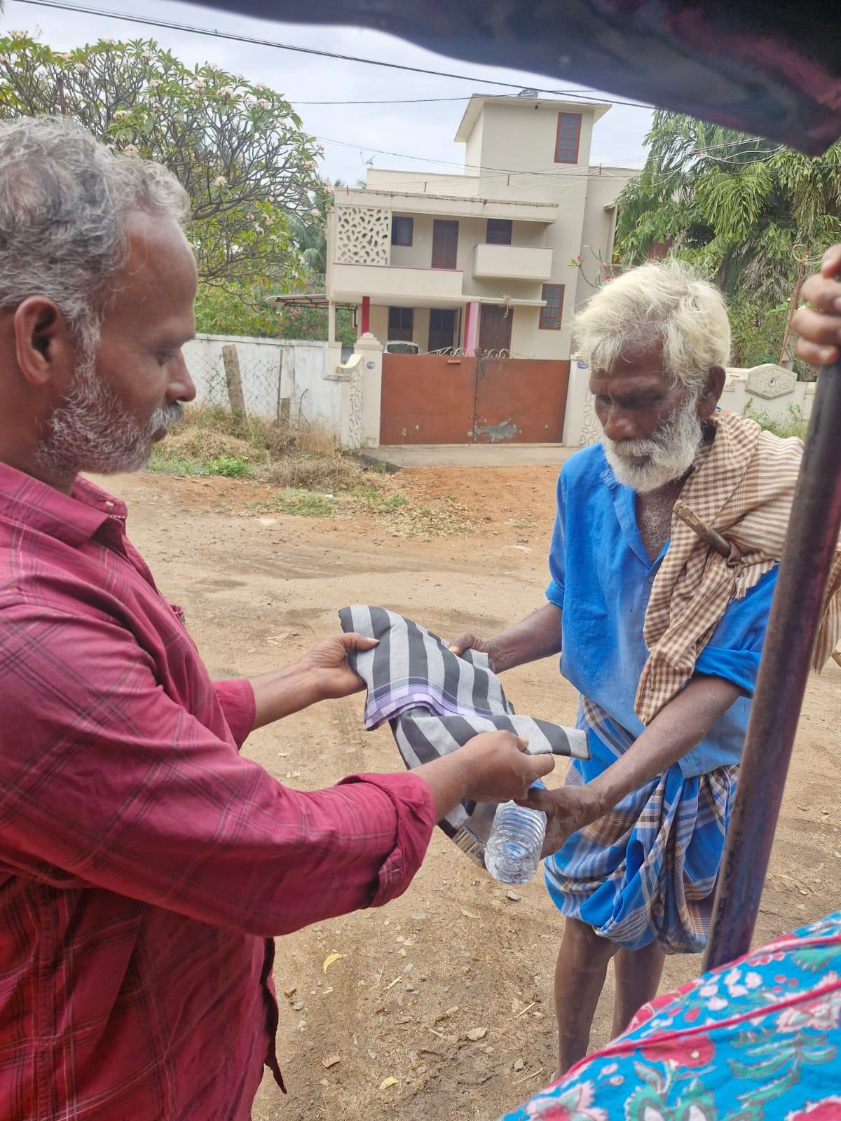 Volunteer handing a cloth to an elderly man by the roadside